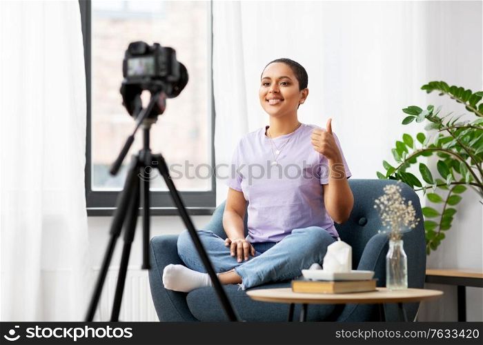 blogging, videoblog and people concept - happy smiling african american female video blogger with camera videoblogging at home and showing thumbs up. female blogger with camera video blogging at home
