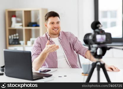 blogging, videoblog and people concept - male blogger with camera recording video at home office. male blogger with camera videoblogging at home