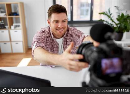 blogging, videoblog and people concept - male video blogger adjusting camera at home office. male video blogger adjusting camera at home office