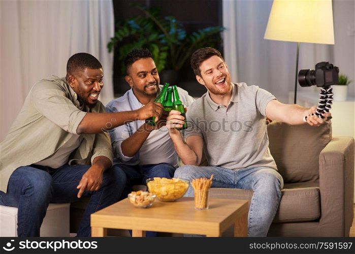 blogging, videoblog and people concept - male video blogger with friends and camera drinking beer with snacks and videoblogging at home at night. male video blogger with friends and camera at home