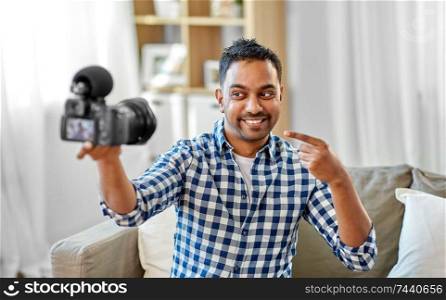 blogging, videoblog and people concept - smiling indian male video blogger with camera videoblogging at home. male video blogger with camera blogging at home