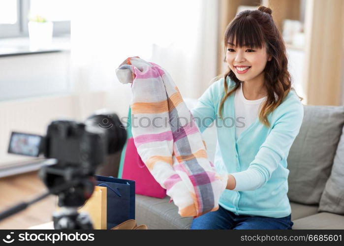 blogging, videoblog and shopping concept - happy smiling asian woman or fashion blogger with scarf, shopping bags and camera recording video blog at home. female fashion blogger making blog about shopping