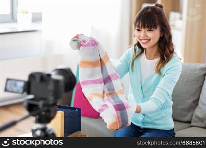 blogging, videoblog and shopping concept - happy smiling asian woman or fashion blogger with scarf, shopping bags and camera recording video blog at home. female fashion blogger making blog about shopping