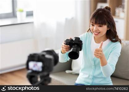 blogging, videoblog and technology concept - asian woman or blogger with photo camera recording video blog at home. asian female blogger with camera recording video