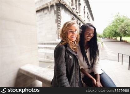 Blond and African American relaxed women smiling outdoors - distorted perspective with tilt shift lens.