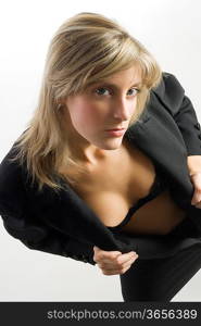 blond and attractive young woman in formal black suit showing her bra in sensual pose