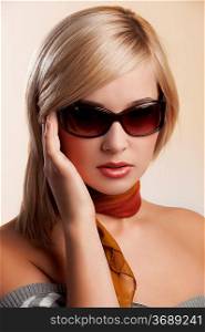 blond and beautiful young woman in a fashion portrait wearing sunglasses jumper and an autumn scarf