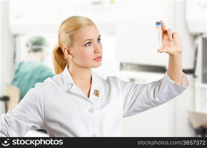 blond and young nurse making a medical analysis and looking at a test tube