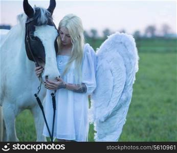 Blond angel looking after the white horse