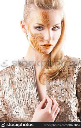 Blond beautiful creature with sequin jacket and creative make up making and hair stylish, she is in frotn of the camera, looks in to the lens and has the right hand near the chest