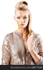 Blond beautiful creature with sequin jacket and creative make up making and hair stylish. She is in front of the camera, looks in to the lens and her left hand is near the chest.