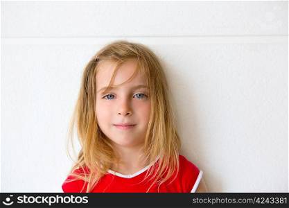 Blond beautiful kid girl smiling on a white wall portrait