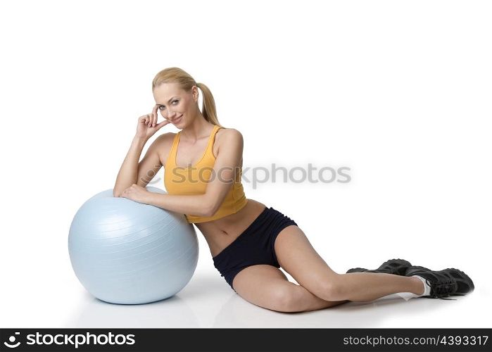 blond beautiful woman in fitness dress sitting near a big ball smiling . NATURAL SKIN