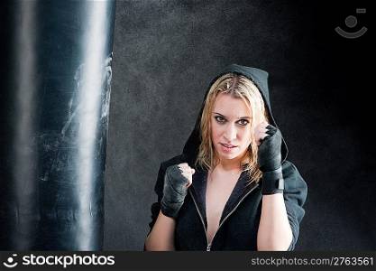Blond boxing woman in black training with punching bag