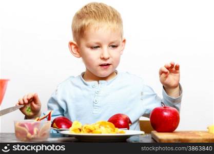 Blond boy child kid preschooler peeling fruit apple eating cooking at home. Happy childhood.