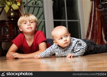 Blond boy with his newborn baby brother indoor