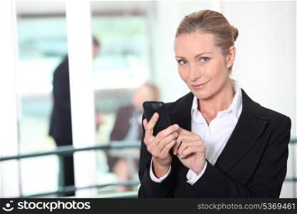 Blond business woman sending text message