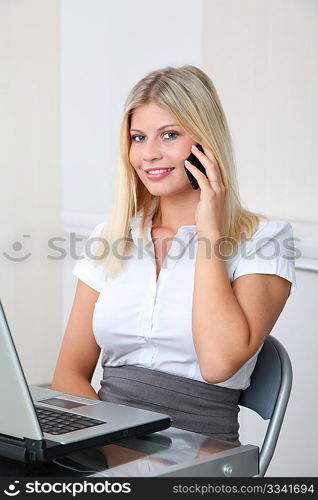 Blond businesswoman doing talking on the phone in the office