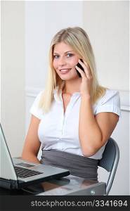 Blond businesswoman doing talking on the phone in the office