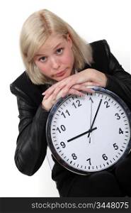 Blond businesswoman leaning on large clock