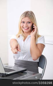 Blond businesswoman pointing at camera