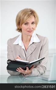 Blond businesswoman sat at desk with diary
