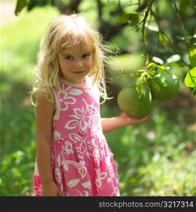 Blond Child Holding Fruit Growing on Tree at Moorea in Tahiti