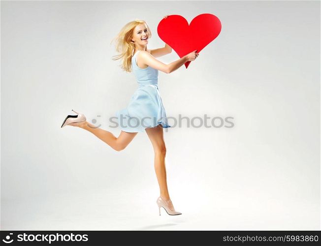 Blond cute lady running with giant heart