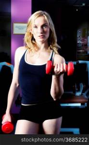 blond cute woman doing exercise with dumbbells in front of mirror forced color