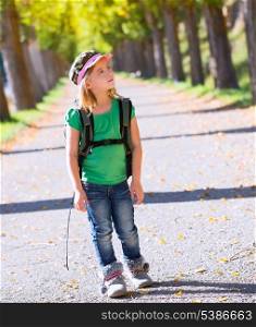 Blond explorer kid girl walking with backpack in autumn trees track
