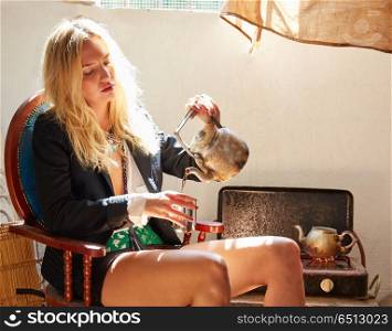 blond fashion girl drinking tea in grunge indoor. blond fashion girl drinking tea in a grunge indoor relaxed on vintage chair
