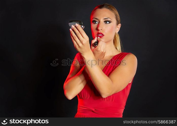 Blond fashion woman lipstick makeup looking at tiny mirror on black background