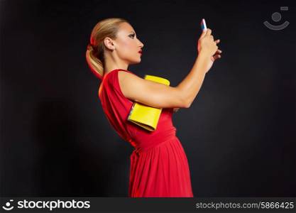 Blond fashion woman selfie photo in smartphone on black background and red dress