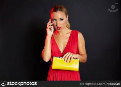 Blond fashion woman talking smartphone on black background and red dress