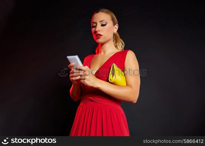 Blond fashion woman writing smartphone on black background and red dress