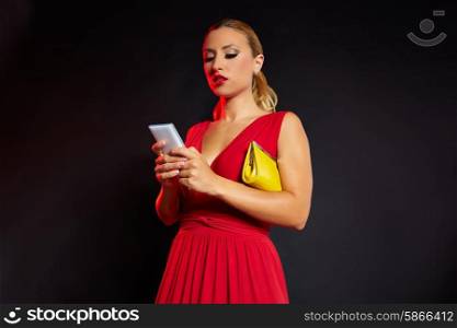 Blond fashion woman writing smartphone on black background and red dress