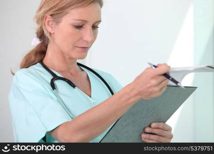 Blond female nurse holding clipboard