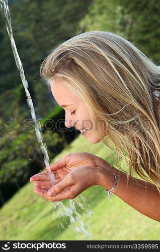 Blond girl drinking water from fountain