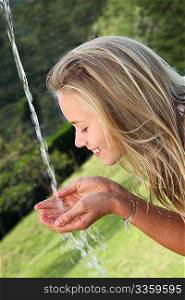Blond girl drinking water from fountain