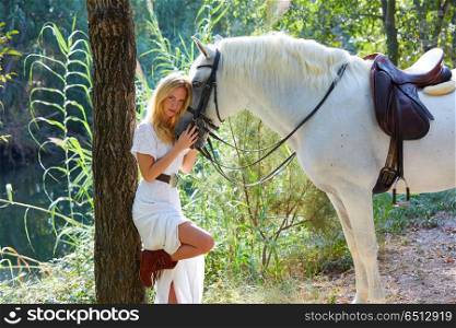 Blond girl hug her white horse in magic forest. Blond girl hug her white horse in a magic light forest near river