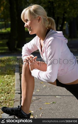 blond girl in fitness dress making gym exercise outdoor in park