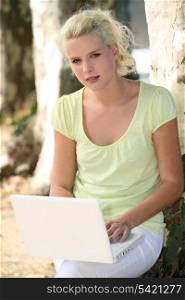 Blond girl in park with laptop