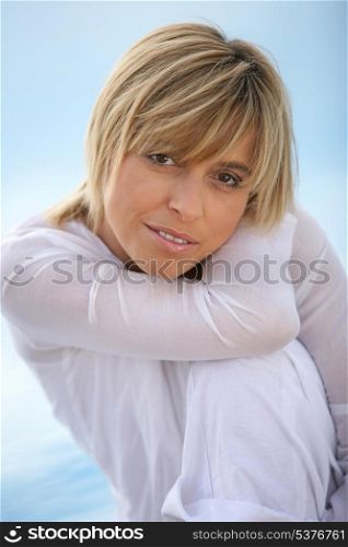Blond girl in white shirt at the seaside