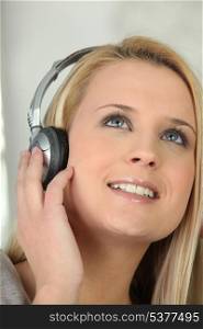 Blond girl listening to music through headphones
