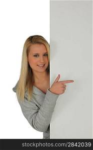 Blond girl pointing at blank panel