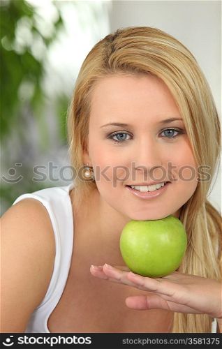Blond girl resting chin on green apple