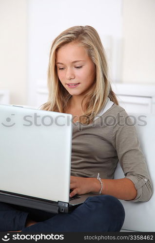 Blond girl sitting in sofa surfing on internet