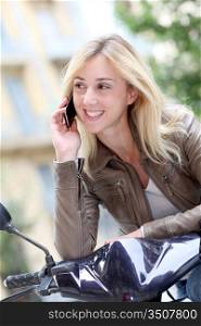 Blond girl sitting on motorcycle with telephone