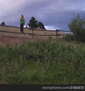 Blond girl standing on fence