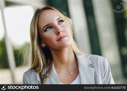 Blond girl wearing casual clothes in the street. Female with blue eyes. Beautiful young caucasian woman in urban background.